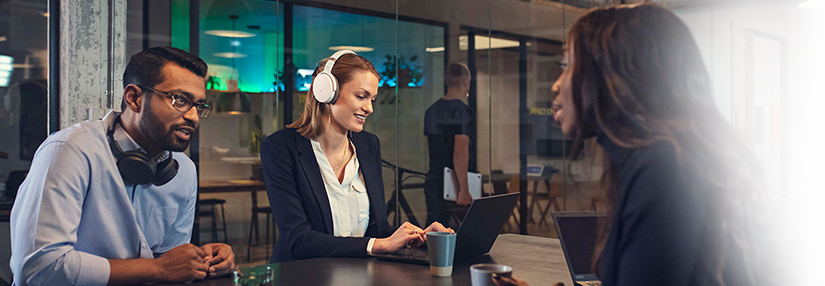 Bureau de travail vitr avec 3 individus assis autour d'une table et portant les casques audio EPOS sans fil