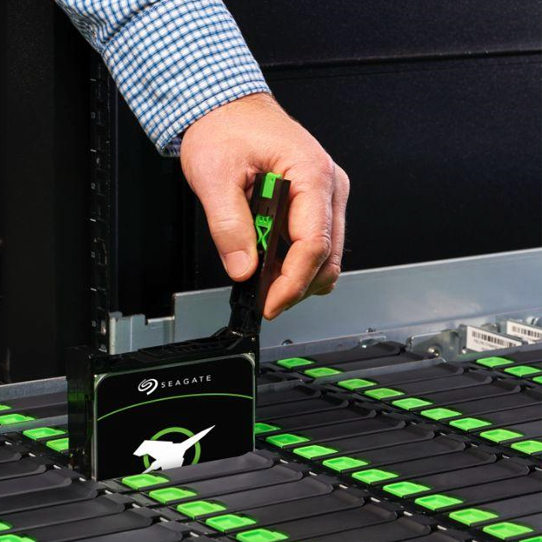 Main d'un homme prenant le disque dur Seagate EXOS X20 dans ses doigts  droite